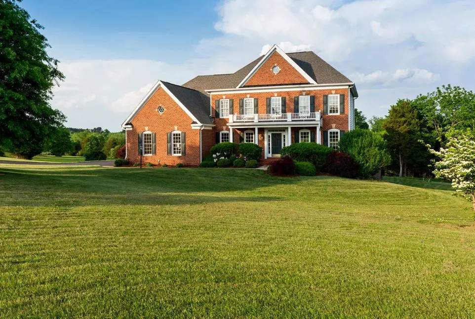 A large brick house sitting on top of a green field.